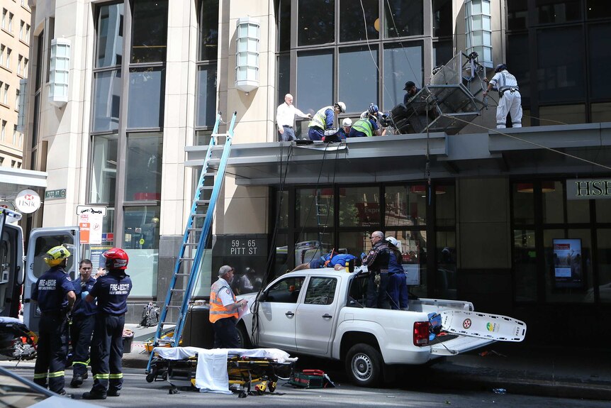 Emergency services help two injured men who fell from a metal window cleaning cage in Sydney's CBD