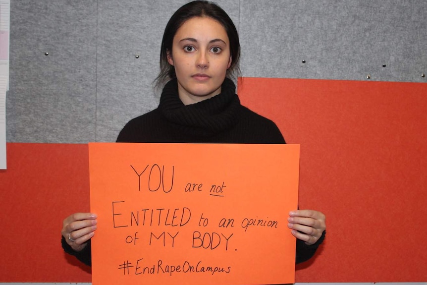 Woman holds orange sign reading: YOU are not ENTITLED to an opinion of MY BODY. #EndRapeonCampus