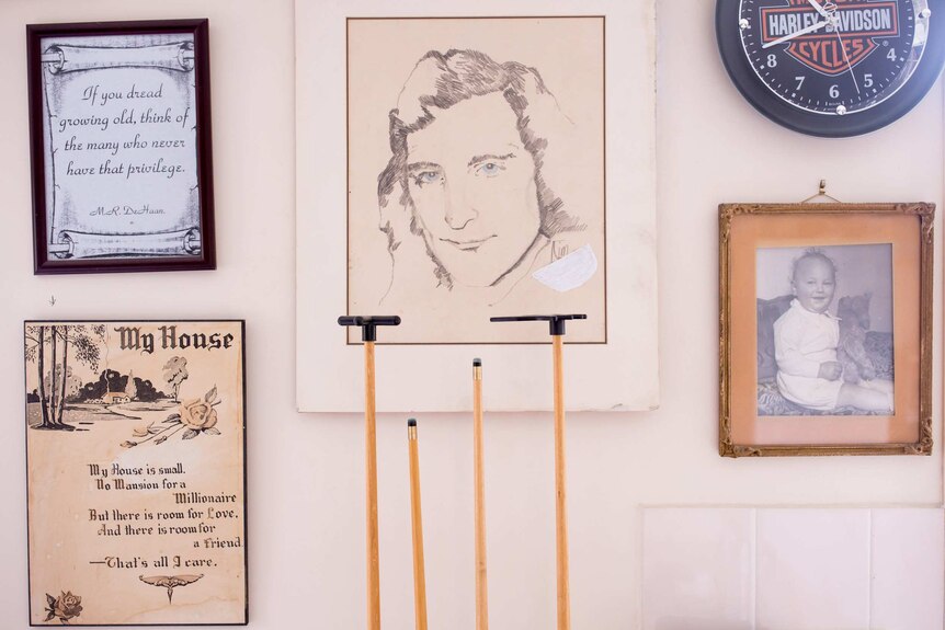 Billiard cues, a hand-drawn portrait and a quote on James Paul's living room wall.