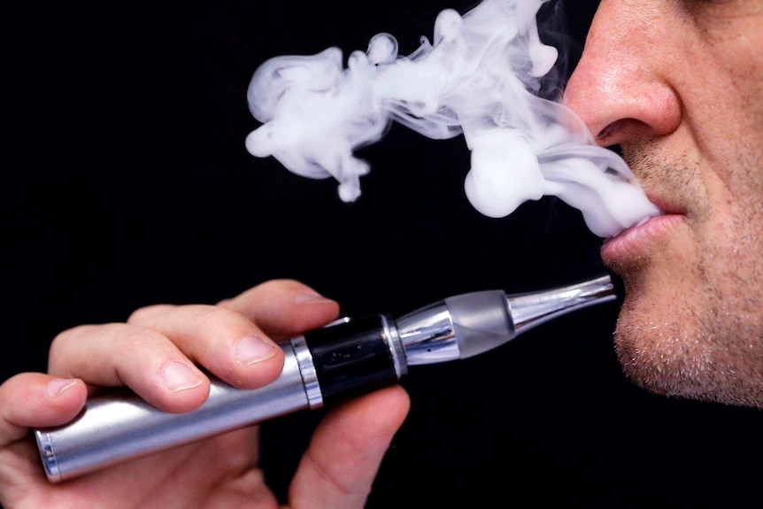 A man uses an electronic cigarette showing vapour.