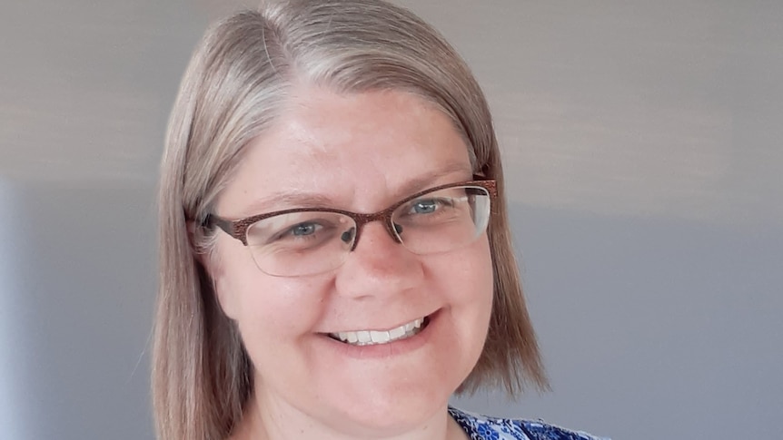 A blonde middle-aged woman with glasses smiles for the camera.