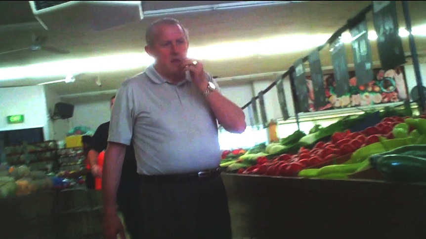 A middle-aged Tony Madafferi scratches his chin while walking through a fruit and vegetable shop.