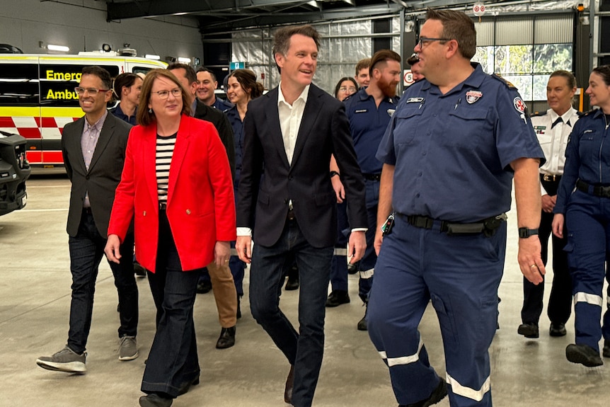 NSW Premier Chris Minns walks with essential service workers at NSW Ambulance Superstation