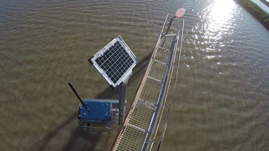 A solar panel and radar device suspended over the water on a flood plain harvesting storage dam.