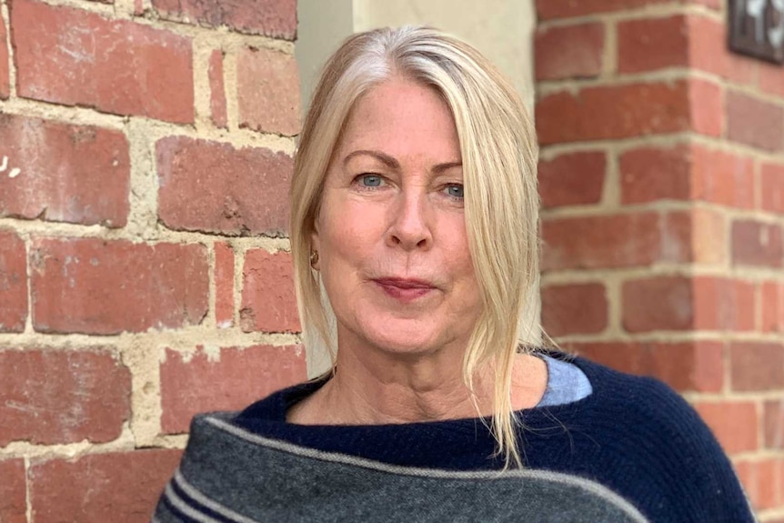 Dr Kate Shaw standing next to a brick wall.