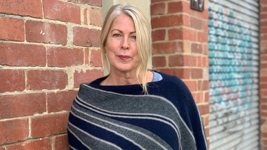 Dr Kate Shaw standing next to a brick wall.