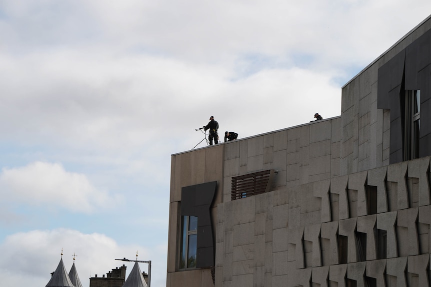 A sniper stands with a rifle on a roof along the Royal Mile