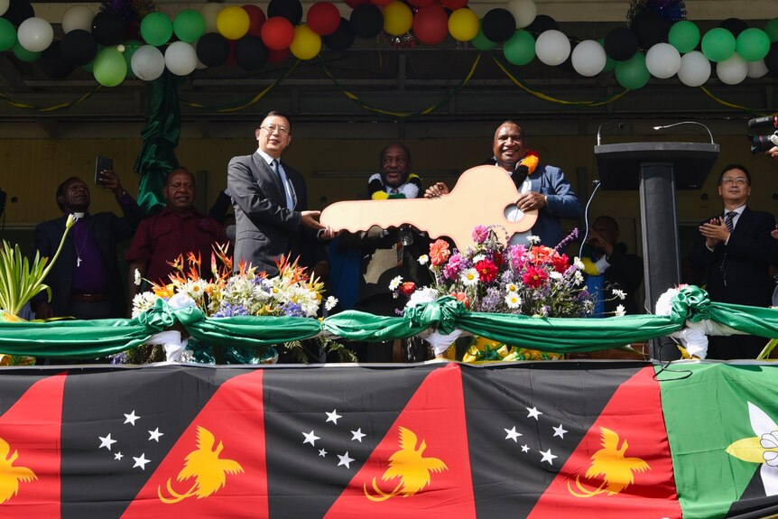 Officials stand on a stage adorned with PNG flags during a ceremony