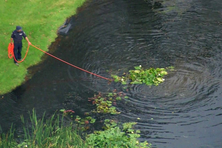 a man holding a rope that goes into a lake