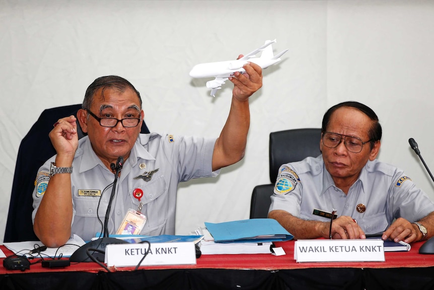 Tatang Kurniadi (left), chief of the National Transportation Safety Committee, holds a model plane during a news conference