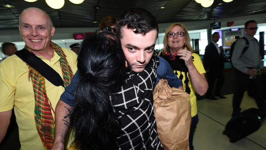 Ashley Dyball is hugged by family members at Brisbane airport.