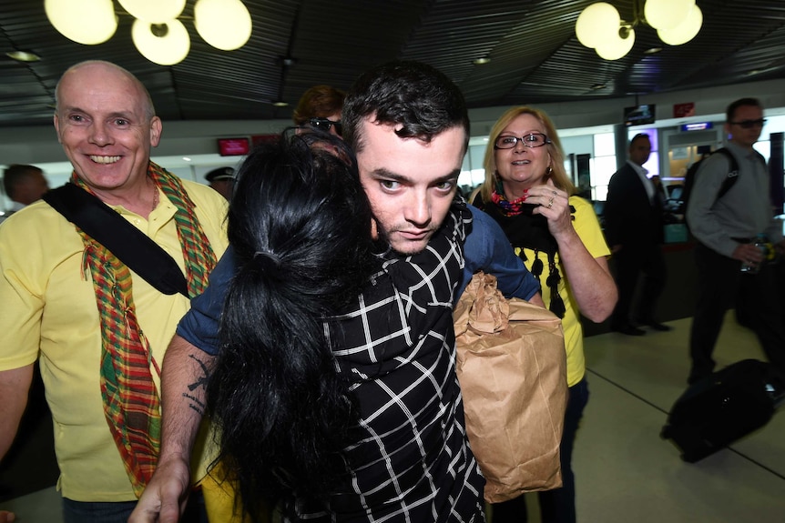 Ashley Dyball is hugged by family members at Brisbane airport.
