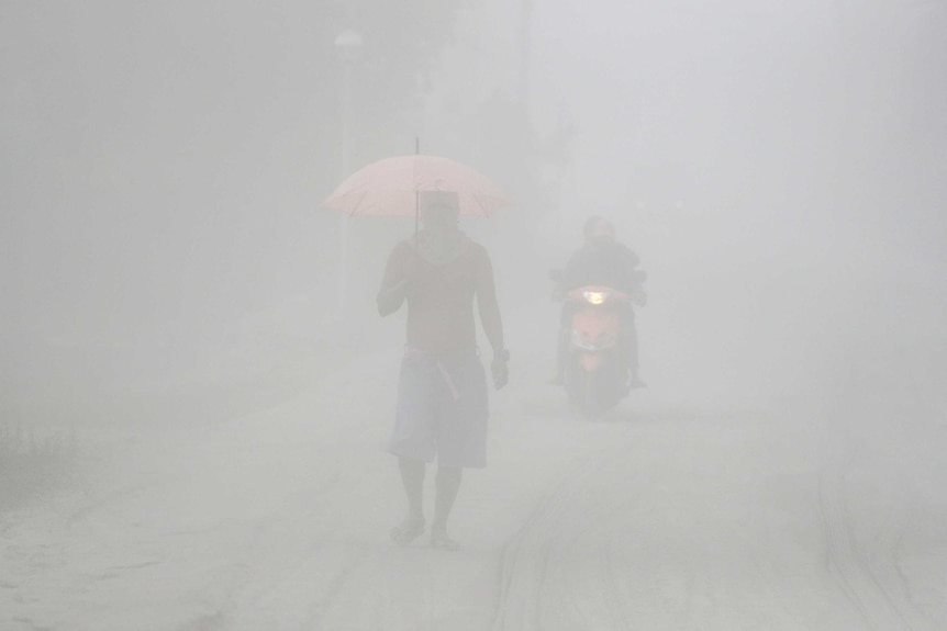 A man walks through a cloud of volcanic ash as he evacuates to safer grounds.