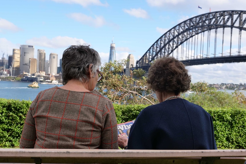 Pia van de Zandt and Fiona Mitchell sit on a bench looking over Sydney Harbour Bridge, May 2020.