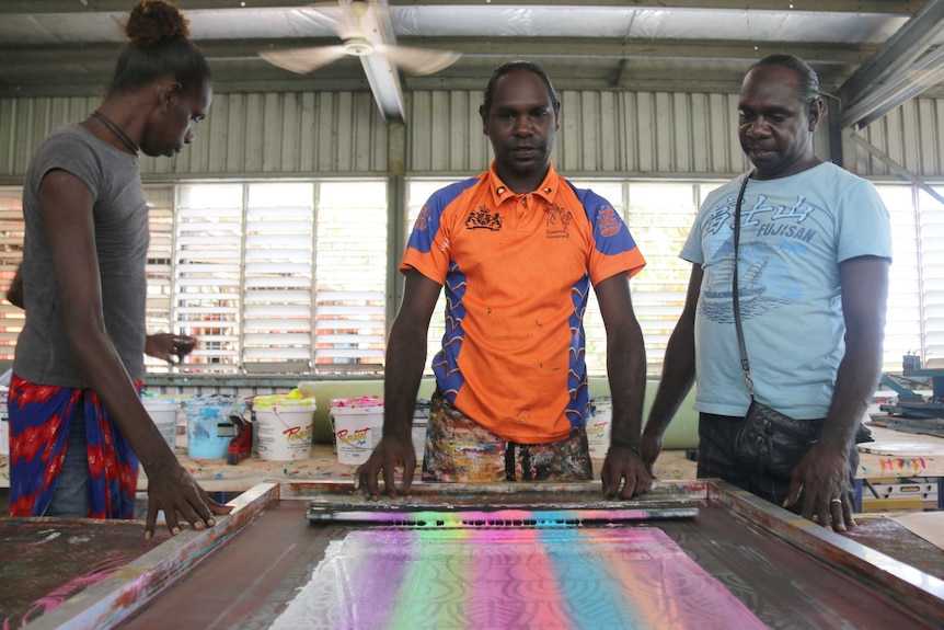 Three trans women in a workshop screen-printing fabric