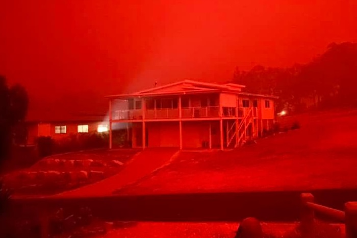 A vivid, red hue colours the entire view of a home in Mallacoota.
