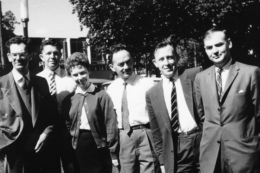 black and white photo of the six members of the lab including Kay Thorne standing outside under a tree dressed formally