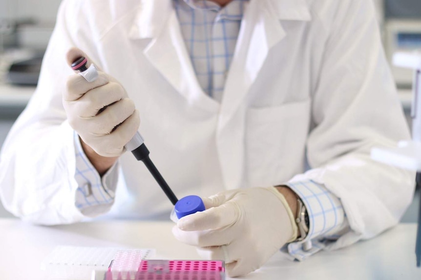 A close up shot of a scientist in a laboratory with a syringe and DNA vials.