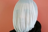 A man wearing a gauze hood on his head.