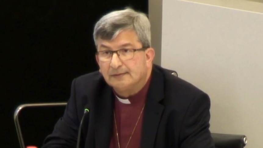 Perth's Archbishop Roger Herft sits and a desk giving evidence at the child sexual abuse royal commission.