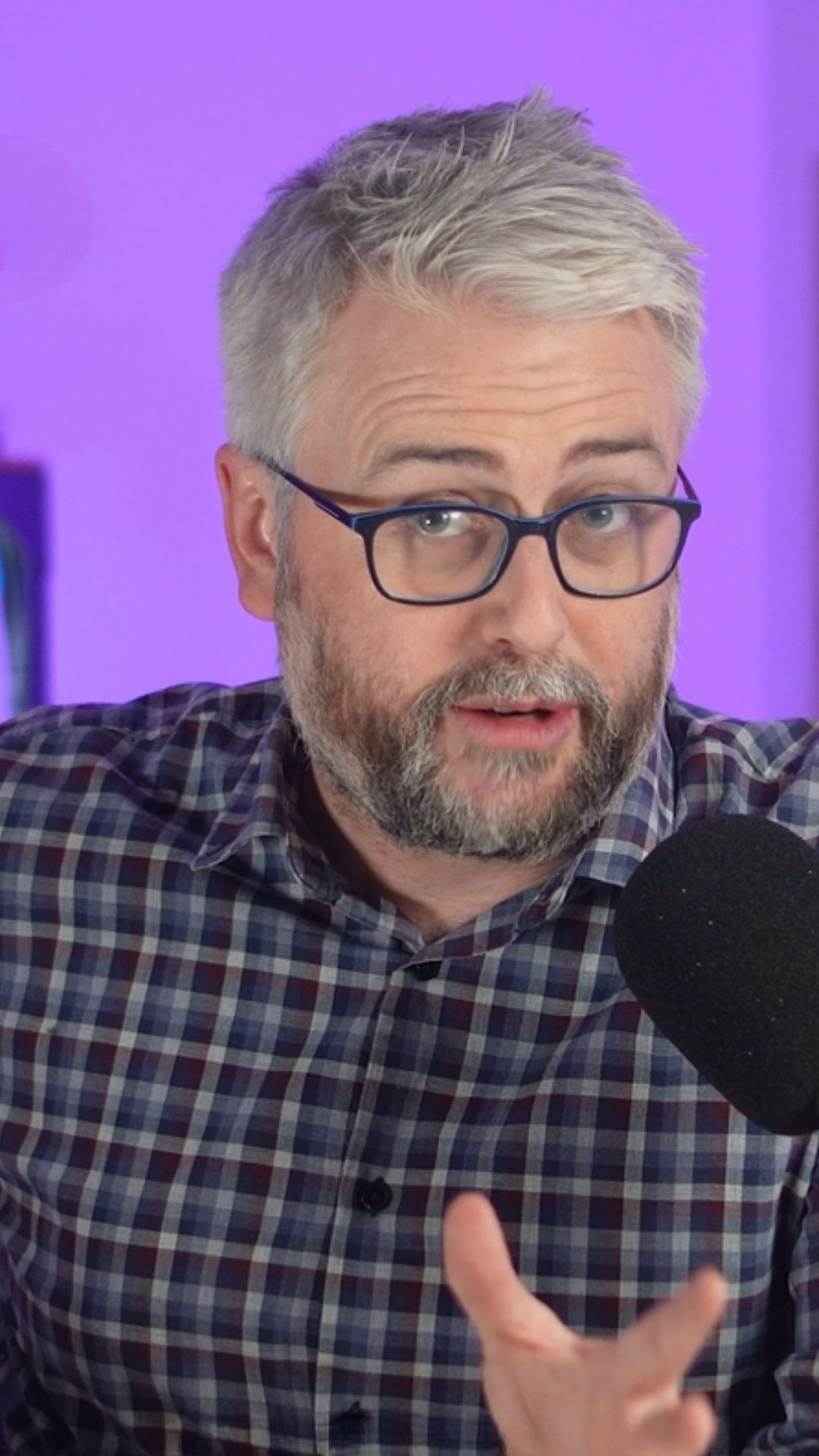 Matt Bevan speaks into a microphone wearing a blue and brown checkered shirt