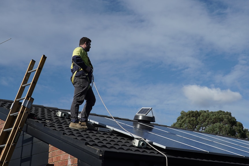 Kevin Schafer standing on a roof inspecting solar panels.