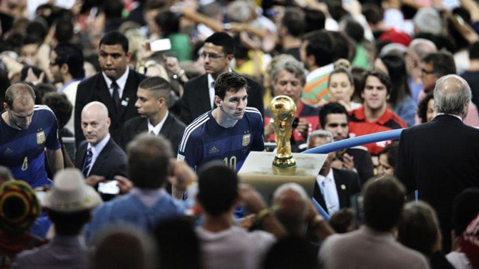 Lionel Messi walking past the FIFA World CUp trophy