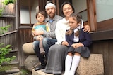 A father, mother, young daughter and son sit in the courtyard of their Japanese home.