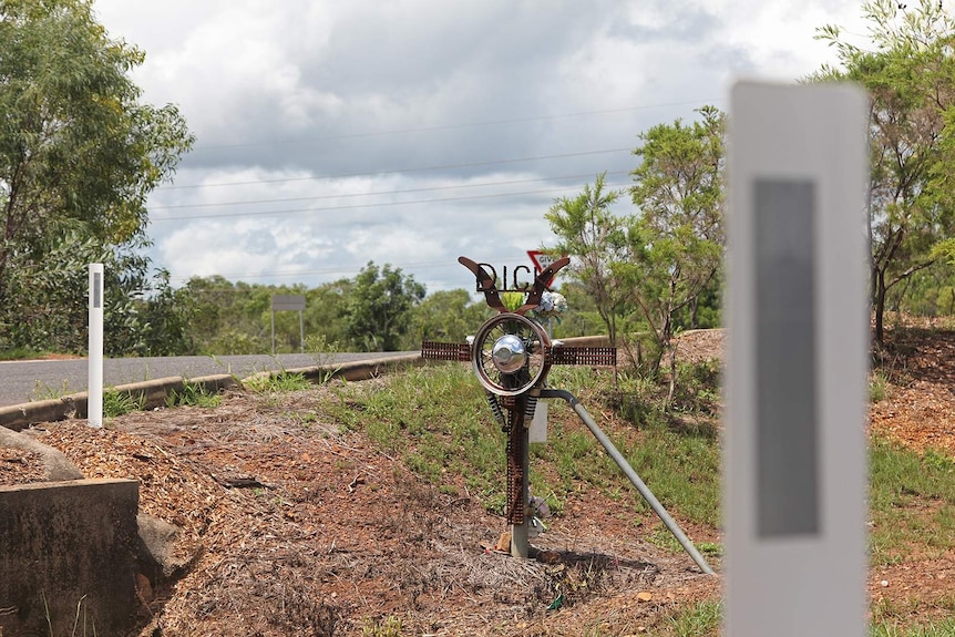 A photo of a metal roadside memorial on the side of the road.