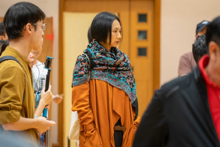 A woman wrapped in a scarf stands in a crowd