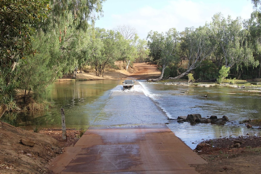 a ute crossing a causeway on a river.