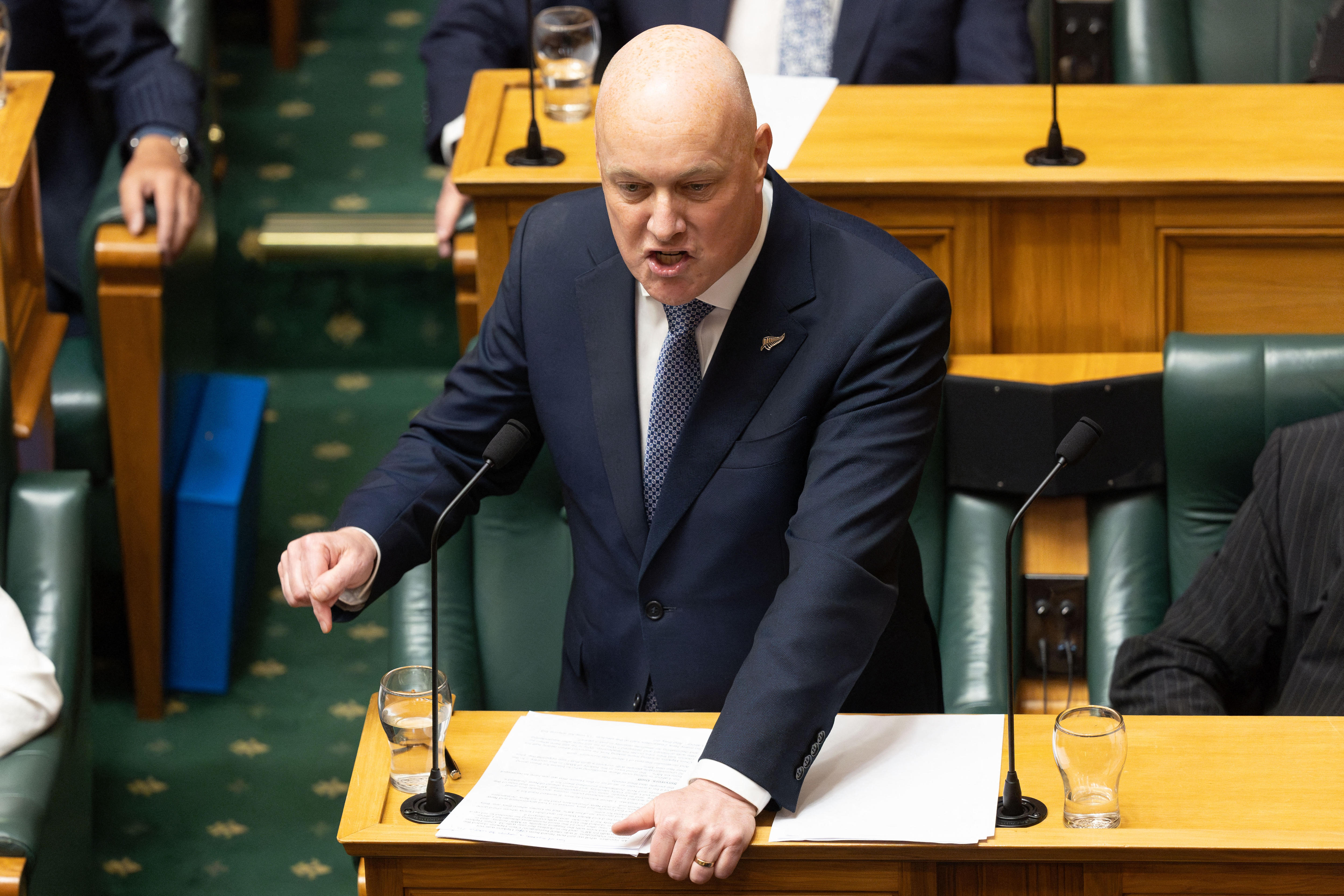 Christopher Luxon in parliament, pointing and looking quite cross. 