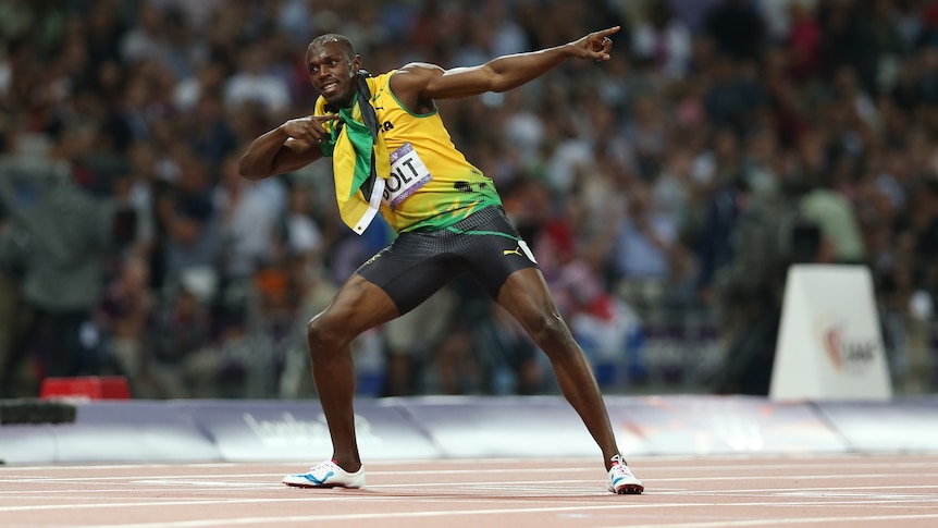 Sprinter Usain Bolt stands in the middle of the track after a big race, posing with his arms spread like a lightning bolt.