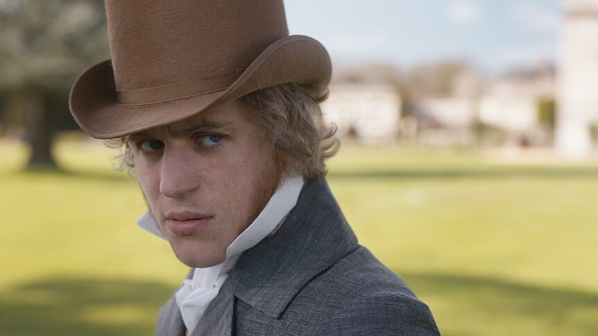 A blonde man in Regency England era tall brown top hat, white blouse shirt and grey jacket, casts a suspicious gaze to his left.