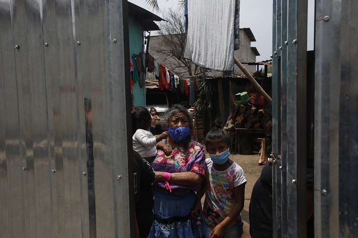 A white flag hangs above members of an artisan doll making family as they wait to receive aid in Antigua, Guatemala.