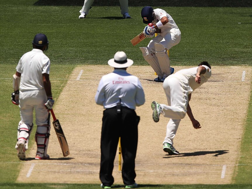 Mitchell Johnson of Australia bowls the ball and hits Virat Kohli of India on the helmet during day three of the First Test match between Australia and India at Adelaide Oval