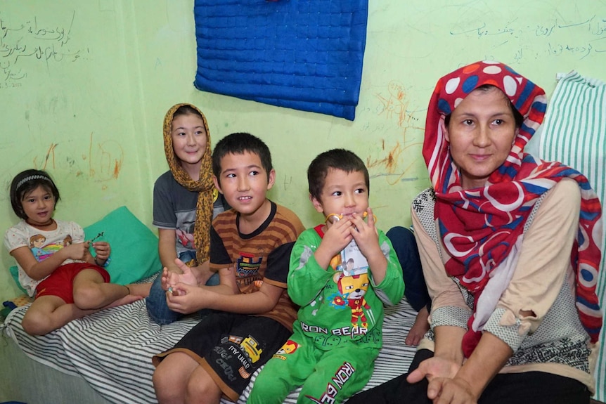 Afghani asylum seeker Rabia Rezai sits on a bed with her children at Jakarta Immigration Detention Centre.
