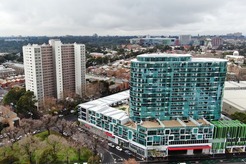 On an overcast day, you view a bright topaz tower situated next to a series of post-war public housing towers.