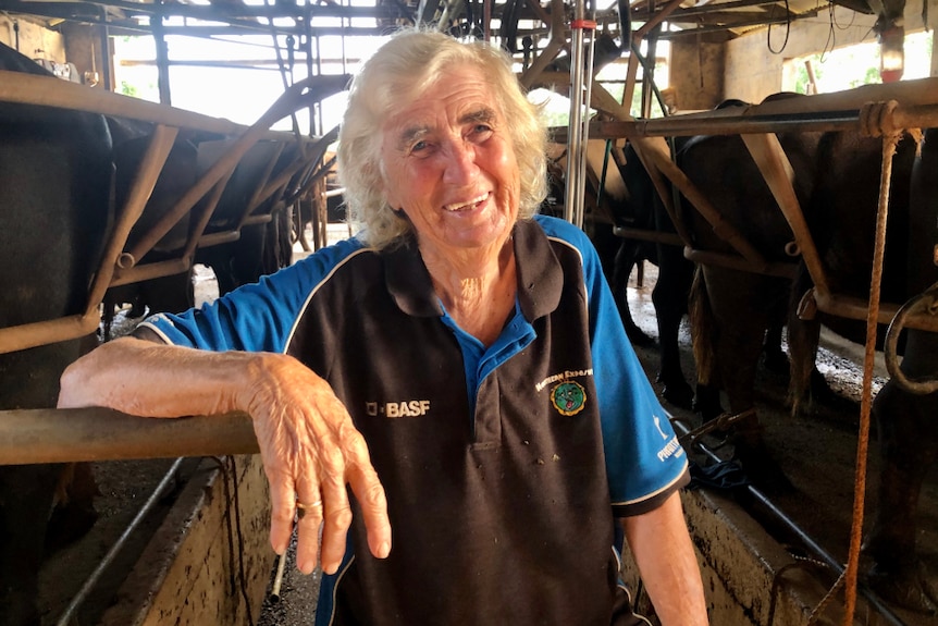 Margaret Thompson smiling with the cows in the bales behind her.