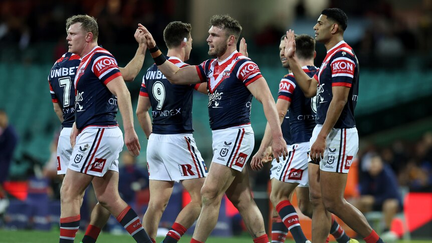 Roosters players high-five each other during an NRL game.