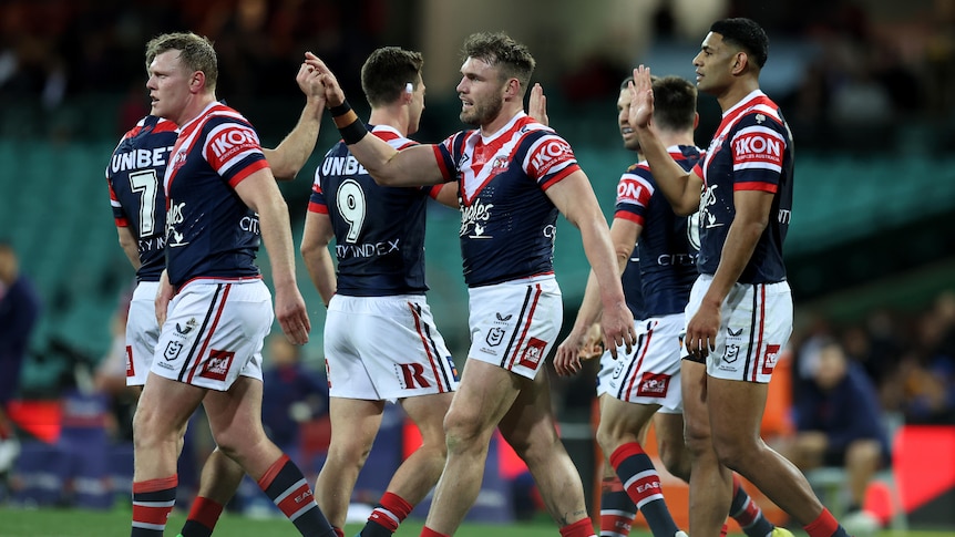 Roosters players high-five each other during an NRL game.