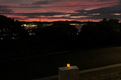 a candle sits on a sill as the sun rises behind