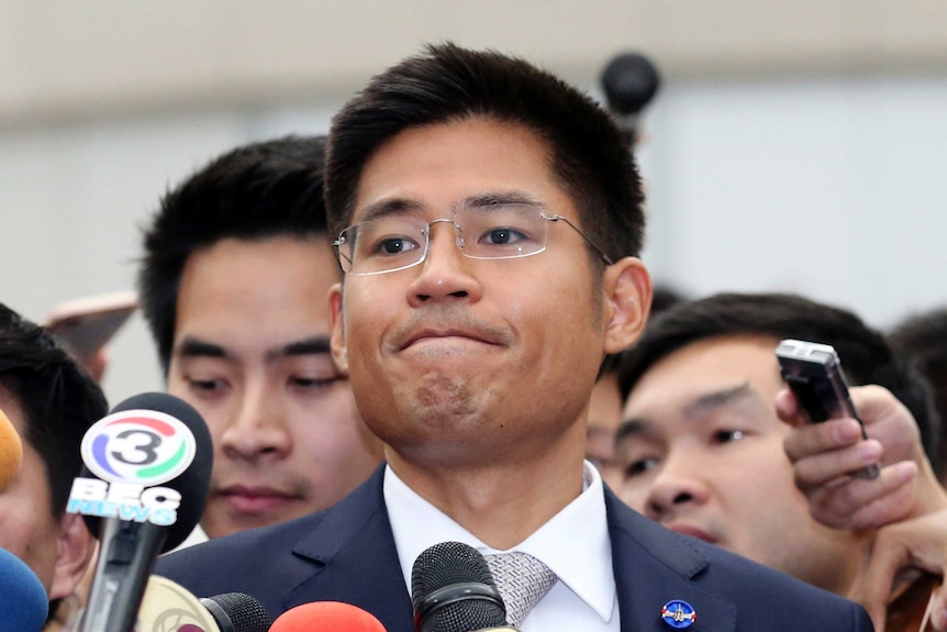 Leader of Thai Raksa Chart party Preechapol Pongpanich presses his lips together as he talks in front of lots of microphones