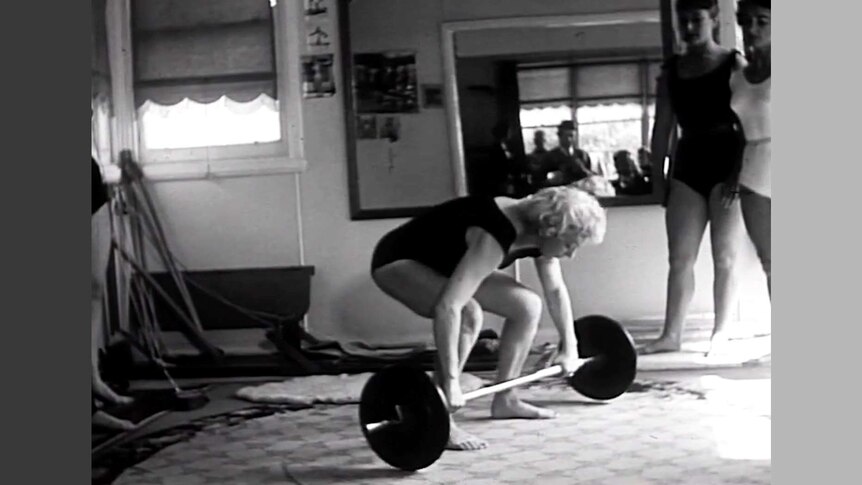 Old photo of woman preparing to lift barbell weights