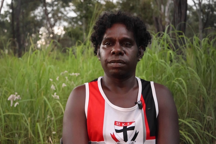 A young man looks at the camera in front of the tall grass in Arnhem Land