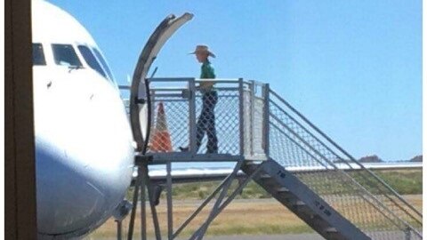 Boy boarding plane on tarmac from steps.