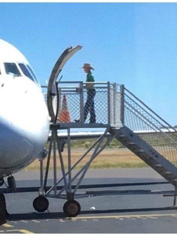 Boy boarding plane on tarmac from steps.