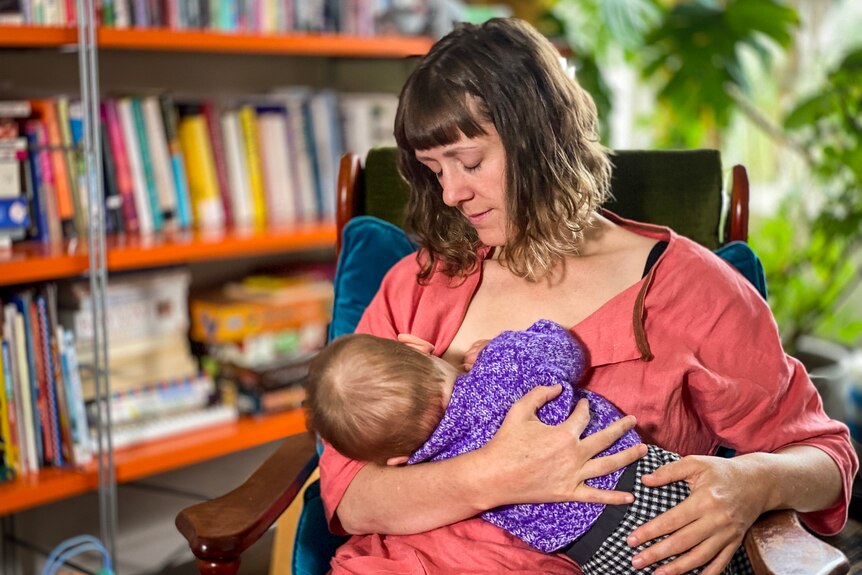 坐在椅子上给婴儿喂​​奶的女人。 