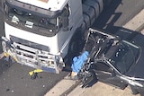 A truck wedged into a car which has its rear end flattened and crushed