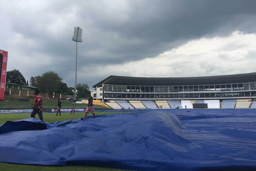 Groundsman apply covers as clouds roll in in Kandy